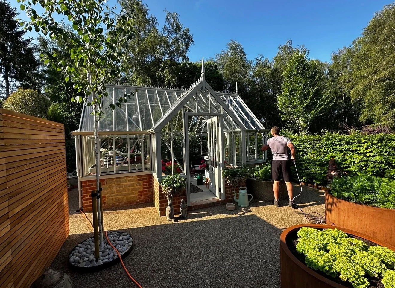 The same greenhouse exterior, glass and ridge cresting cleaned with a water-fed pole